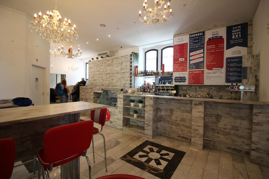 米兰New Generation Hostel Milan Center Navigli的餐厅设有酒吧,配有红色椅子和吊灯