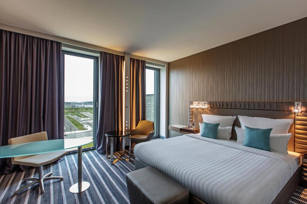 舍讷费尔德Steigenberger Airport Hotel Berlin的酒店客房设有一张床、一张书桌和窗户。