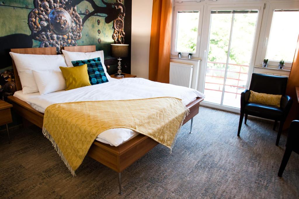 米库洛夫Boutique Hotel Golf Garni的一间卧室配有一张大床,提供黄色和蓝色的枕头
