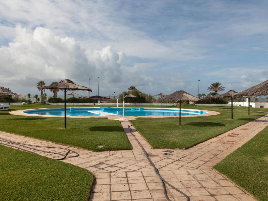CampanoPinar de Don Jesus Sagitario的一个带遮阳伞和草地的大型游泳池