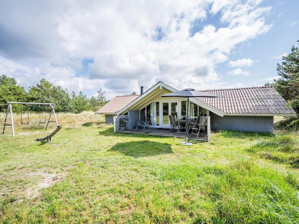 布拉万德Holiday home Blåvand CXLVI的田野上的一个小房子,带秋千
