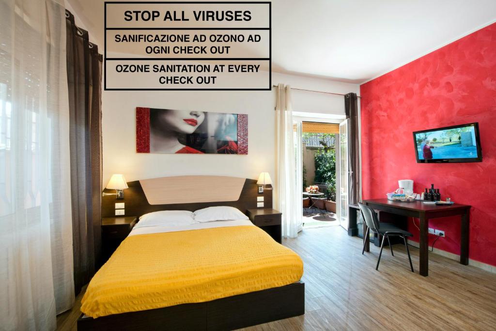 罗马梵蒂冈84号酒店的一间卧室配有一张床、一张桌子和一道红色的墙壁