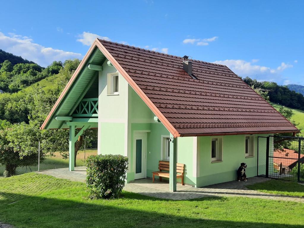 SevnicaHoliday Home Neokrnjena Narava的一座小的绿色和白色房子,里面养着狗