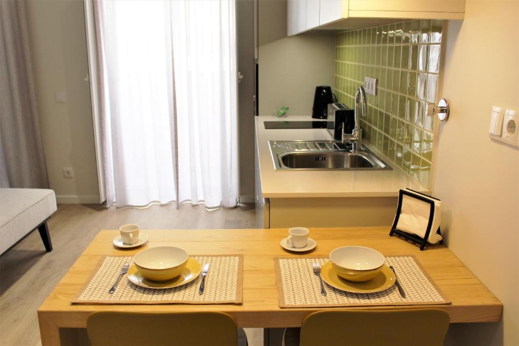 法鲁Cardeal Suites & Apartments的厨房配有木桌,上面放有盘子和碗
