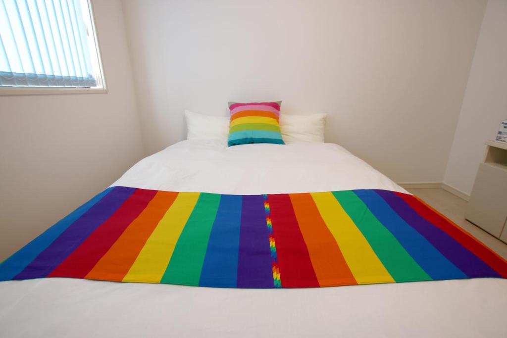 金武KOEI FARM LODGE -SEVEN Hotels and Resorts-的床上的彩虹毯子