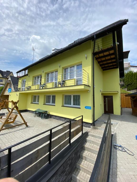 维斯瓦Pokoje i apartamenty Aga Centrum的黄色的房子设有阳台和庭院