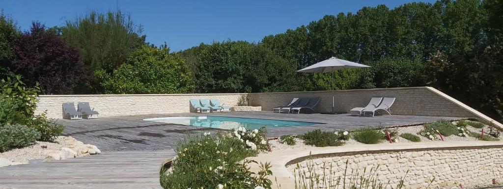 塞雷斯特Les Prairies de l'Encrême的一个带两把椅子和遮阳伞的游泳池