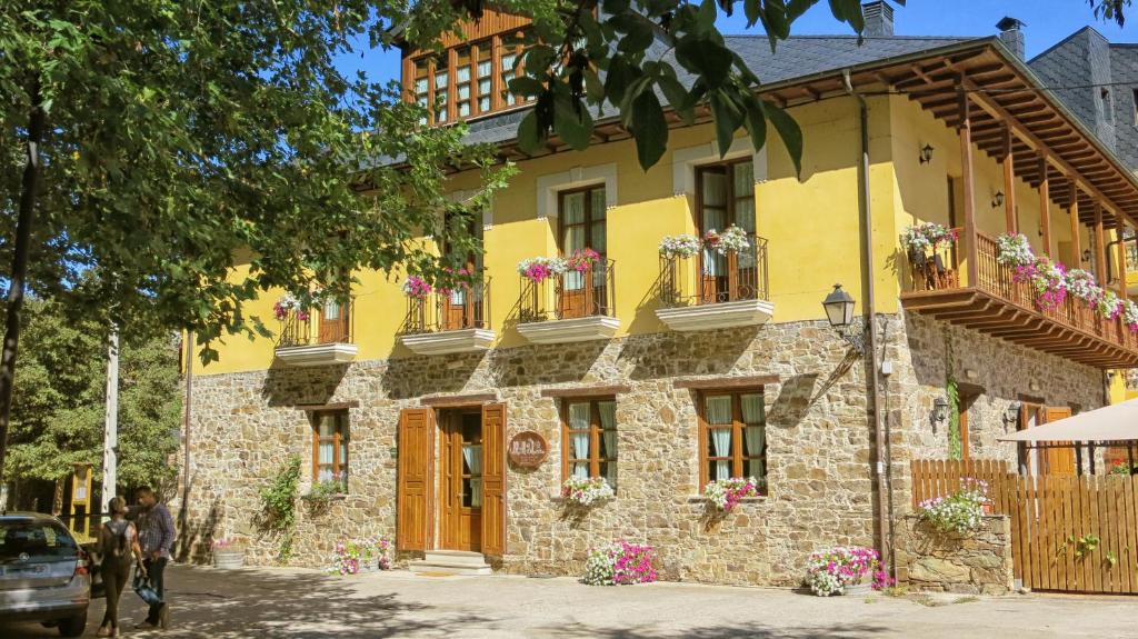 San Esteban de Valdueza锡伦西奥山谷酒店的黄色建筑,窗户上放着花盒