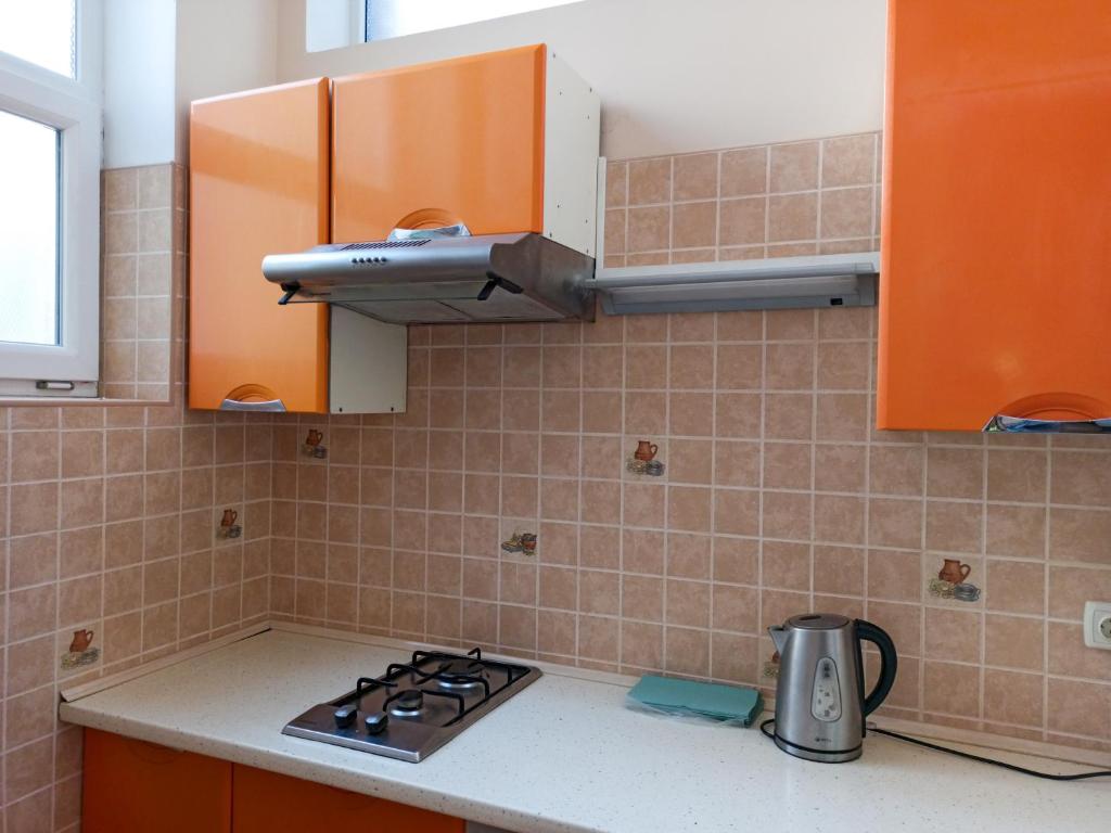 利沃夫PANORAMI Apart Hostel in Lviv的厨房配有橙色橱柜和炉灶烤箱