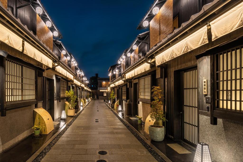 京都Nazuna Kyoto Tsubaki St.的两座种植盆栽植物的建筑之间的空洞小巷