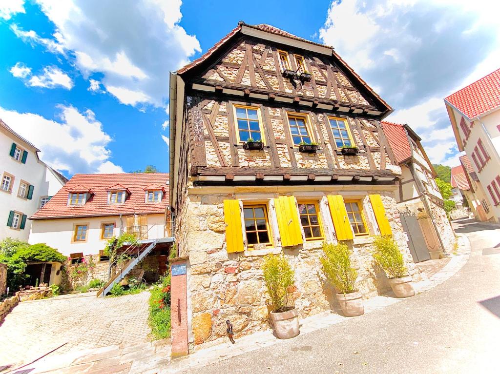 GleisweilerLANDHOTEL 1707 by Landgasthof Zickler的街道上一座带黄色百叶窗的古老石头建筑