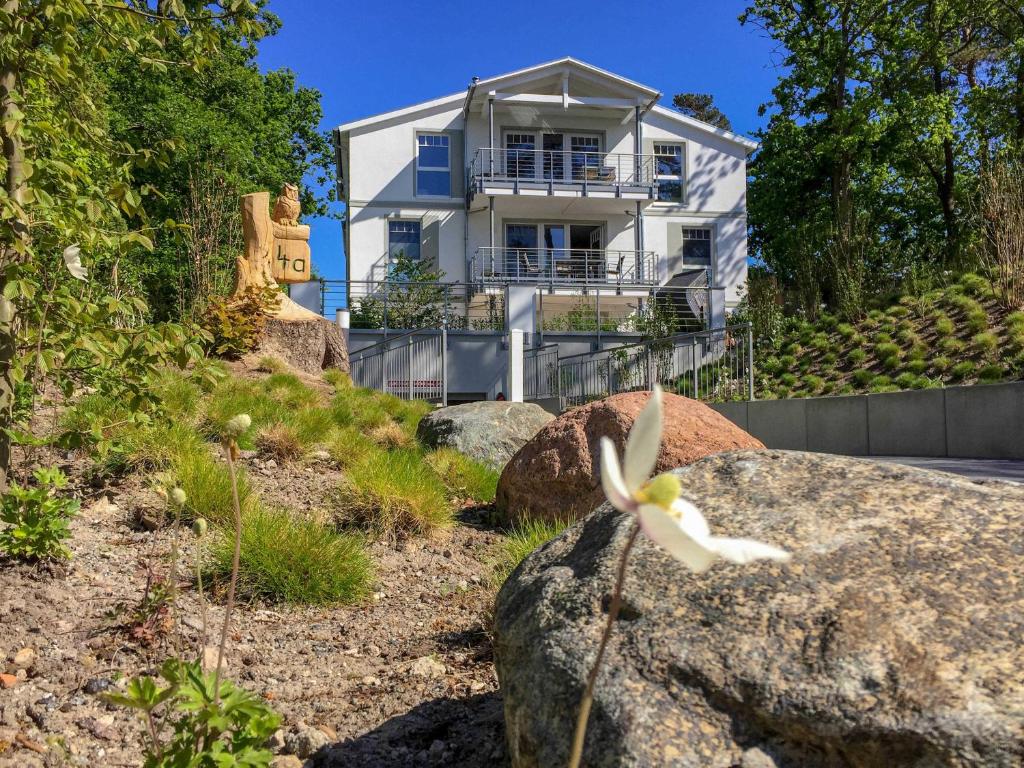宾茨Villa "Düne 4" - WG1 im EG mit Terrasse strandnah的山丘上一座房子,有岩石和花