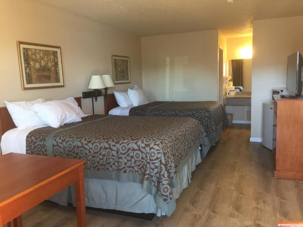 梅萨Travel Inn - Mesa的酒店客房设有两张床和一张桌子。