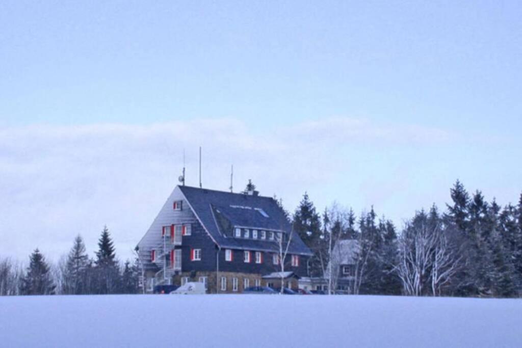 库罗阿尔滕堡Berghaus Falkenhorst的雪覆盖的田野中间的大房子