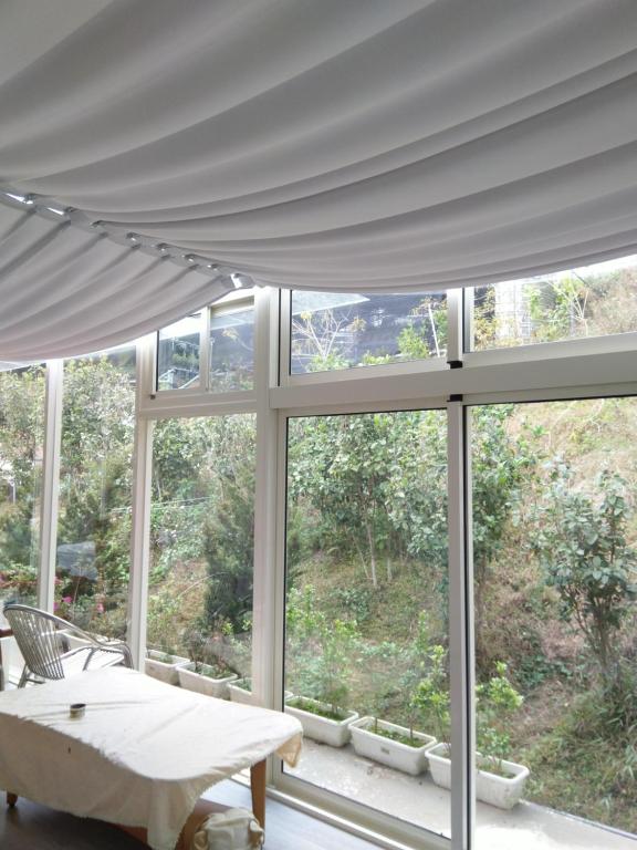 三义云庭兰园的客房设有带白色窗帘的大窗户。