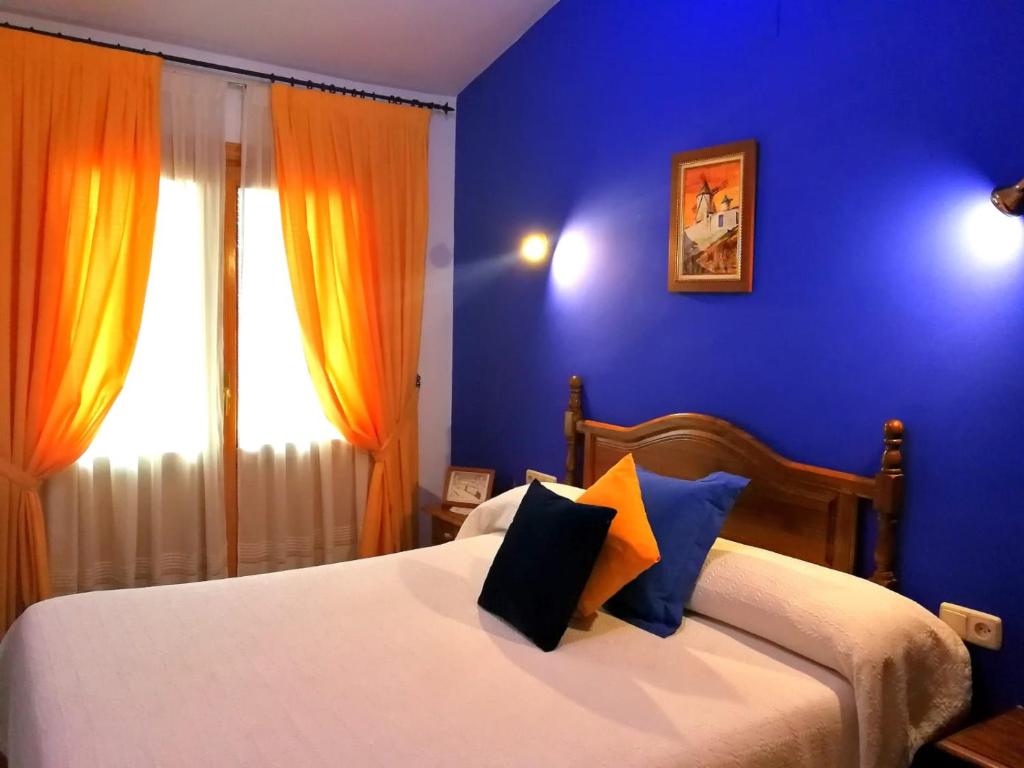 坎波德克里普塔纳Hostal Restaurante Ego's的一间卧室配有一张蓝色墙壁的床和一扇窗户