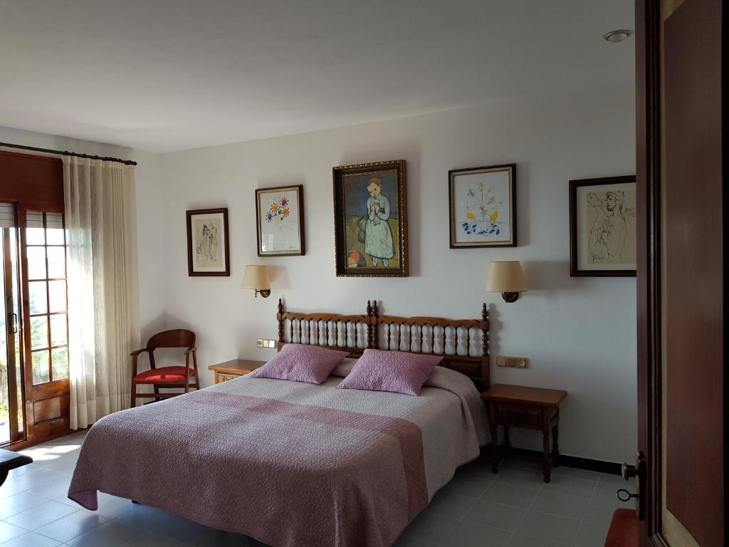 巴古尔Hostal Sa Barraca - Adults Only的一间卧室配有一张床,墙上挂着一些图片