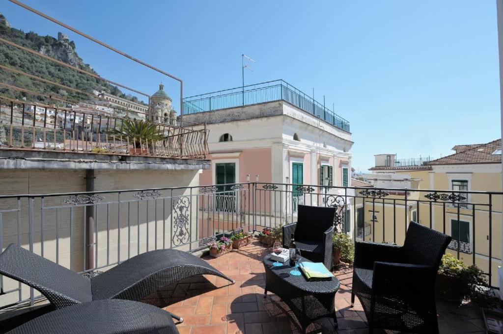 阿马尔菲Residenza Del Duca Rooms & Apartments的大楼内的阳台配有椅子和遮阳伞
