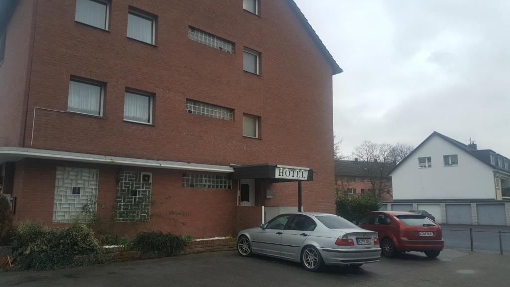 科隆Hotel Heideklause的两辆汽车停在砖楼前