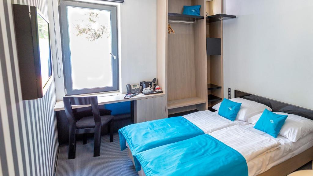 波普拉德水城滨江酒店的一间卧室配有一张床、一张书桌和一个窗户。