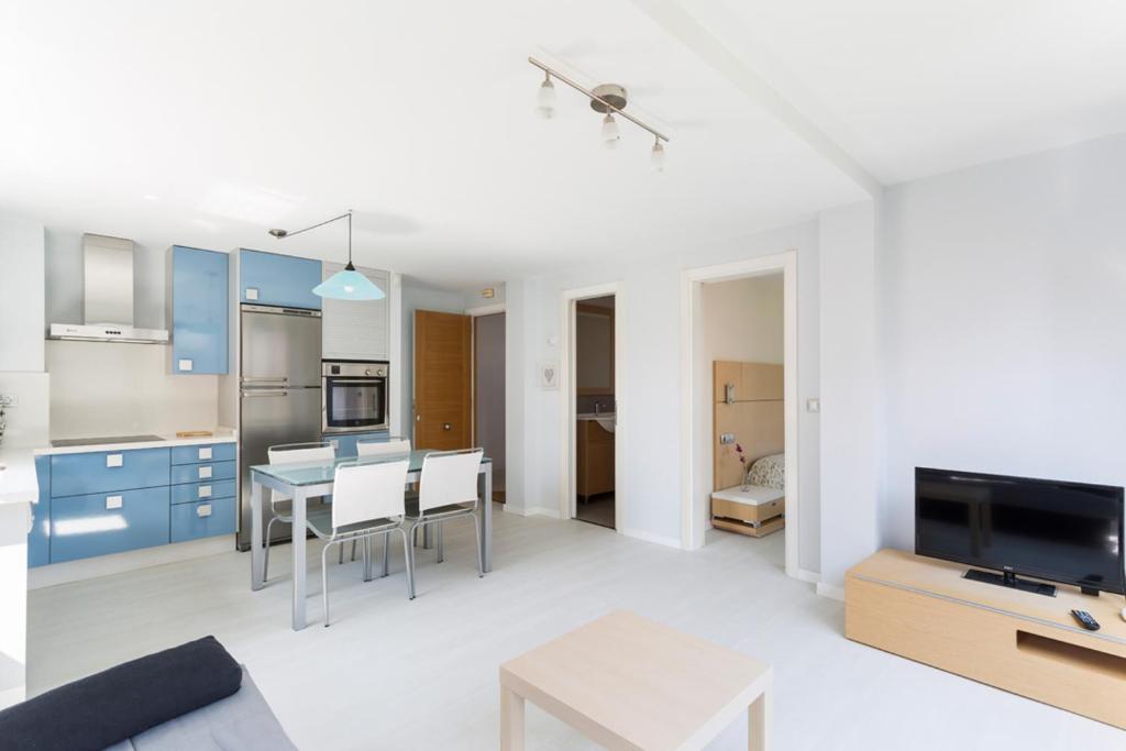 米尼奥Housingcoruña Apartamento Playa Miño 04的厨房以及带蓝色橱柜和桌子的用餐室。