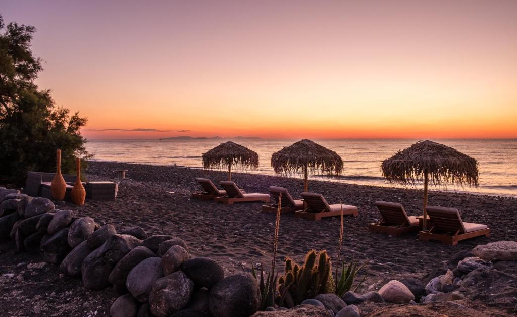 卡马利Beach Houses Santorini的海滩上设有椅子和草伞,还有大海