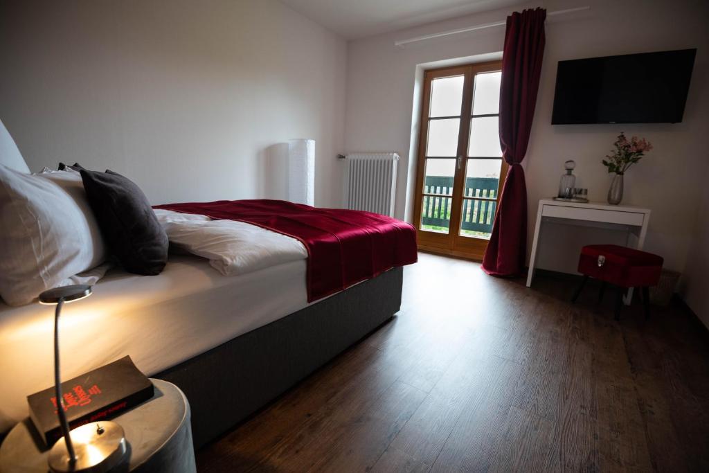 基姆湖畔贝尔瑙Landgasthof Hittenkirchen的一间卧室配有一张带红色毯子的床和窗户。