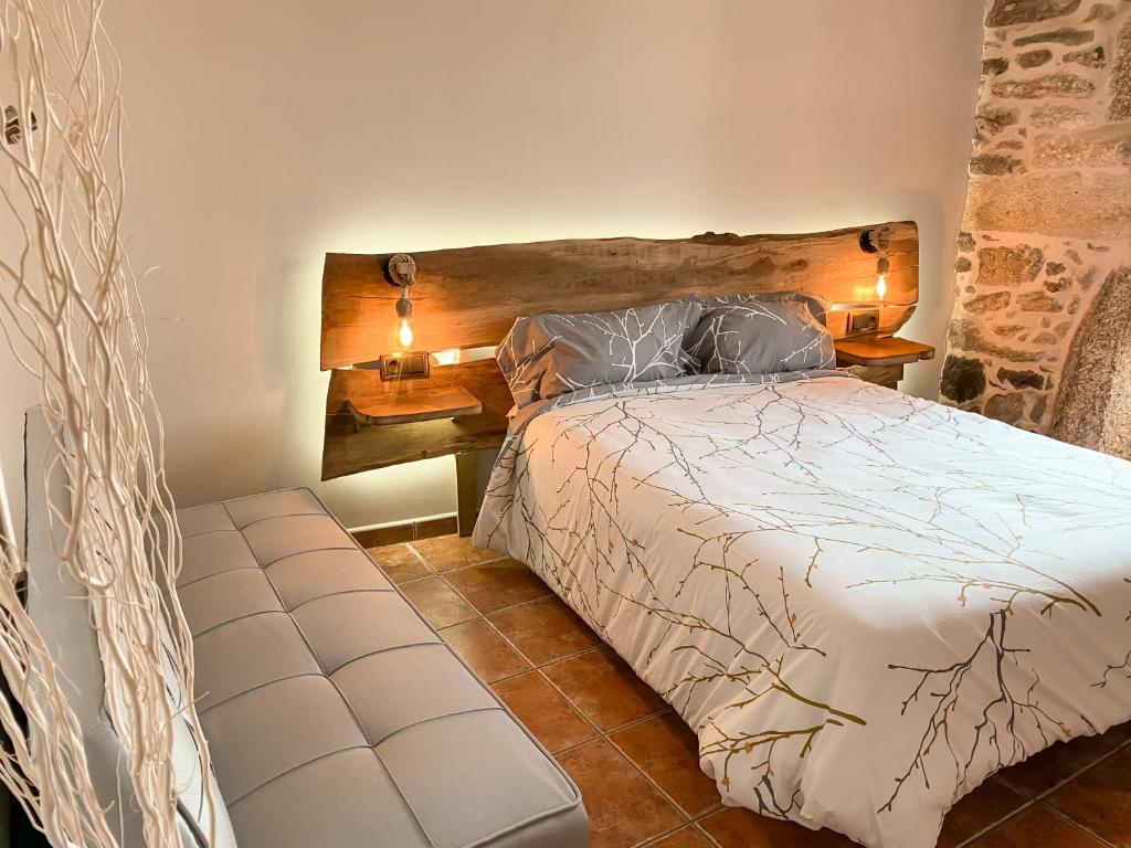 PorqueirósCasa As Fontes的一间卧室配有一张床、两盏灯和一张长凳