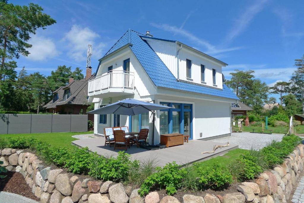 奥茨塞巴德·迪尔哈根TIDENHUS的白色的房子,设有蓝色的屋顶和庭院