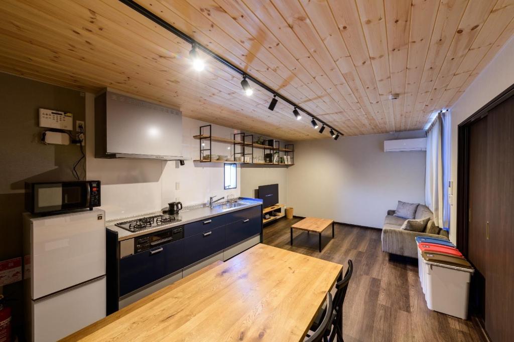 佐世保Rakuten STAY HOUSE x WILL STYLE Sasebo 102的厨房和带木制天花板的客厅