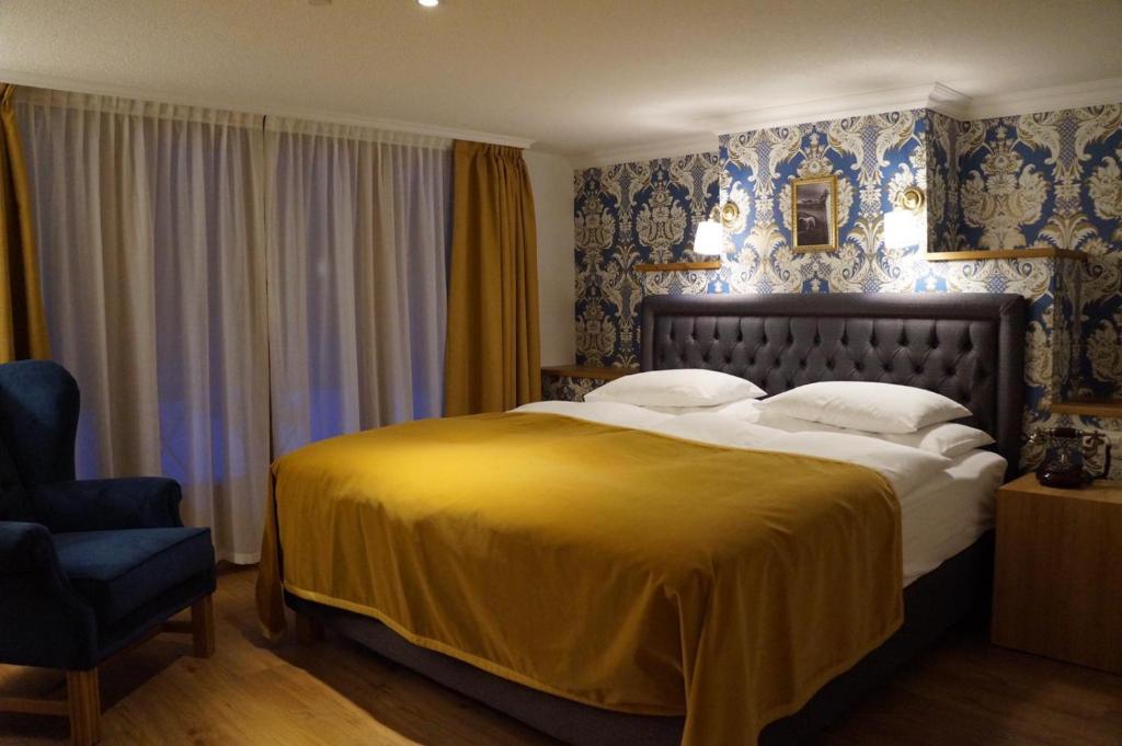 采尔马特Hotel Walliserhof Zermatt的一间卧室配有一张大床和一把椅子