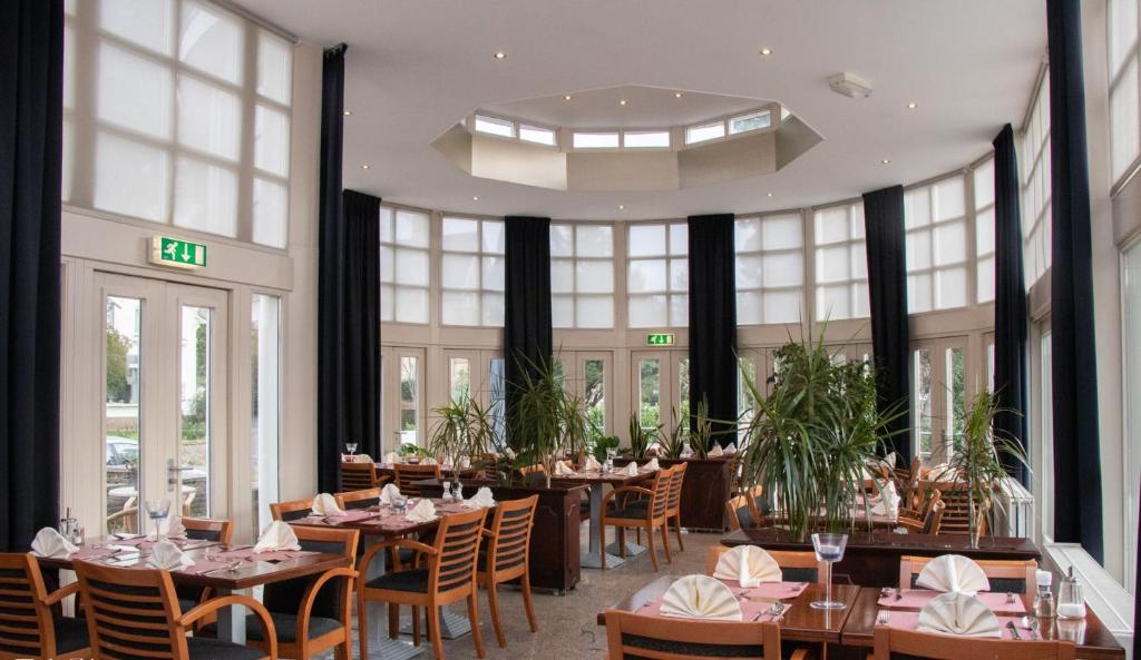 法尔肯堡法肯堡2000酒店的餐厅设有桌椅和大窗户。