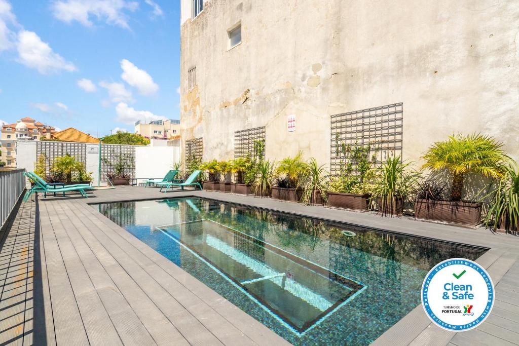 埃斯托利尔Chalet Estoril Luxury Apartments的植物群前的游泳池