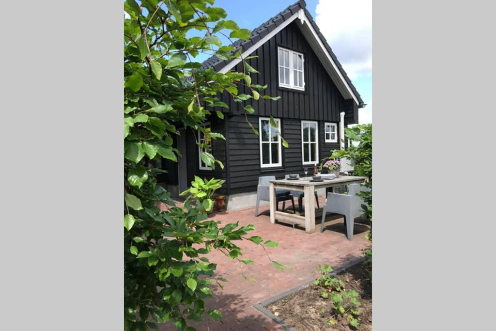 Hollandsche RadingUniek houten huis nabij bos en plassen的前面有一张野餐桌的黑色房子