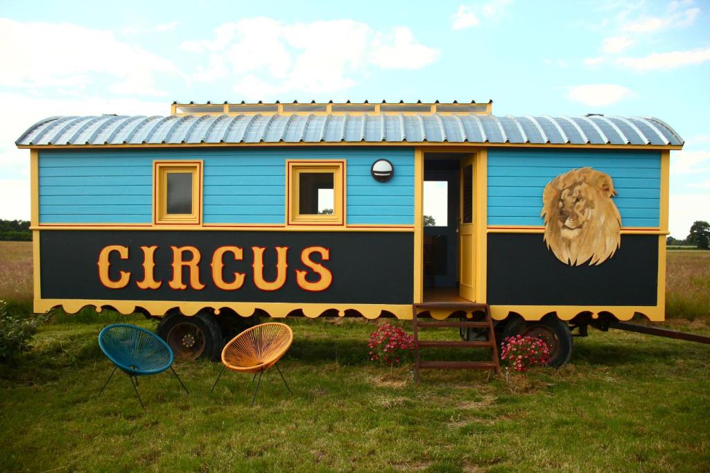 BeaulonLa roulotte CIRCUS des Grillots的一辆蓝色和黄色的火车车在场上展示