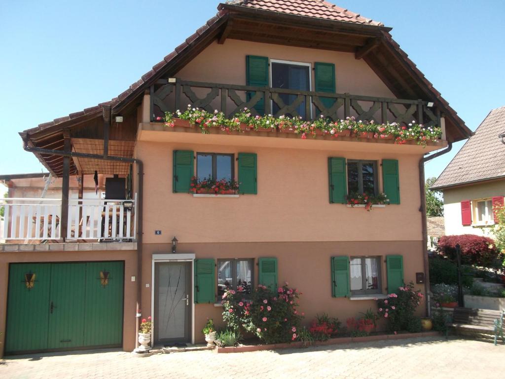 Traubach-le-BasGite les Rosiers的一座带绿色百叶窗和阳台的房子