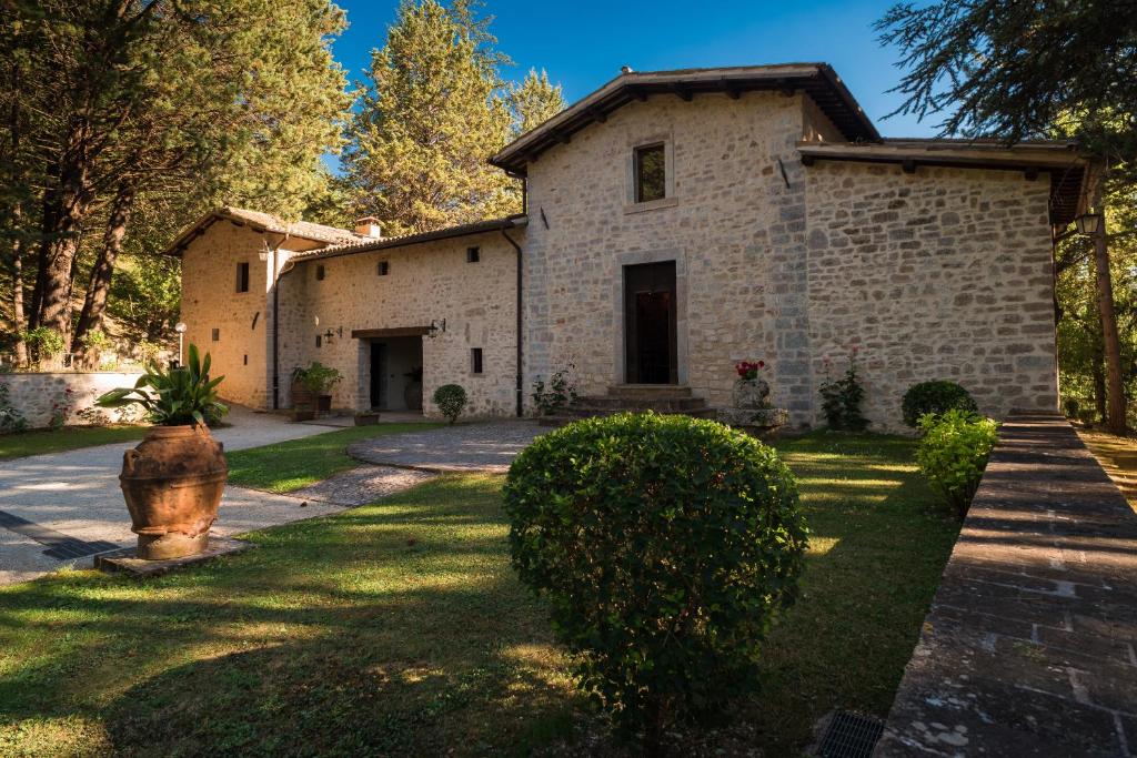 SellanoConvento di Acqua Premula的一座大型石屋,设有一座带灌木的庭院