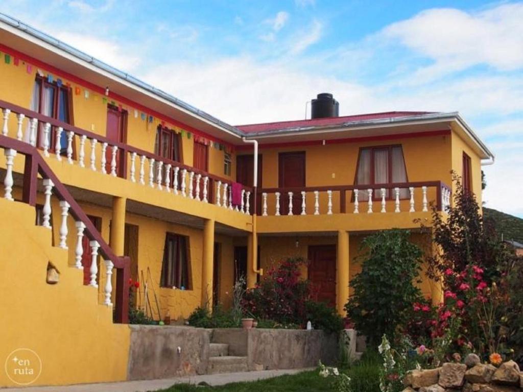 Comunidad YumaniHostal Utama的黄色房子,设有阳台和鲜花