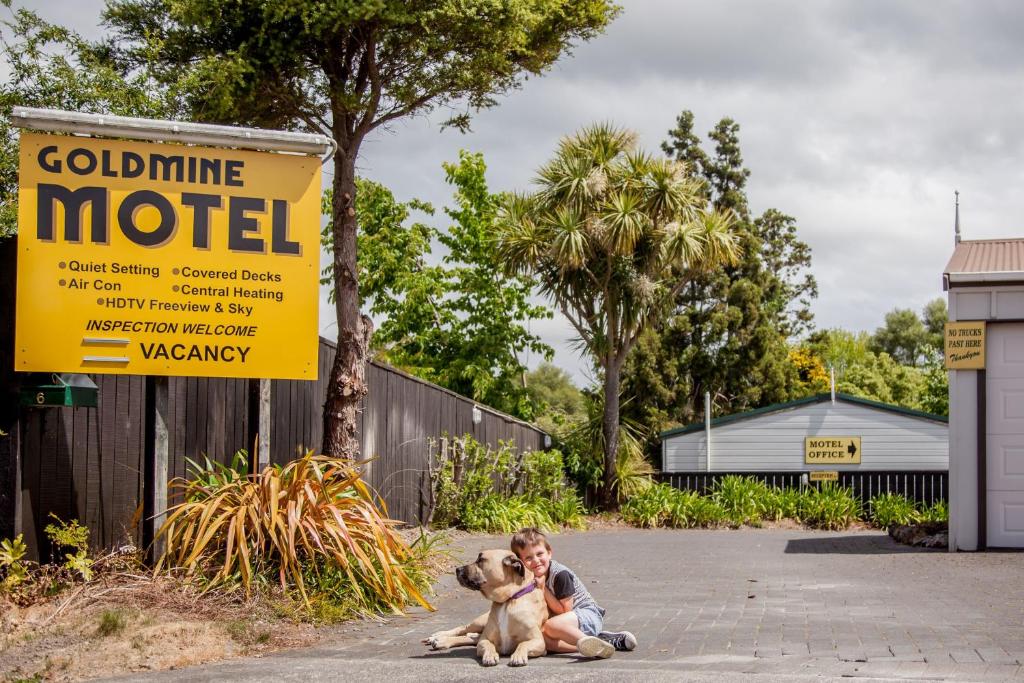 怀希Goldmine Motel的坐在标志旁的男孩和狗