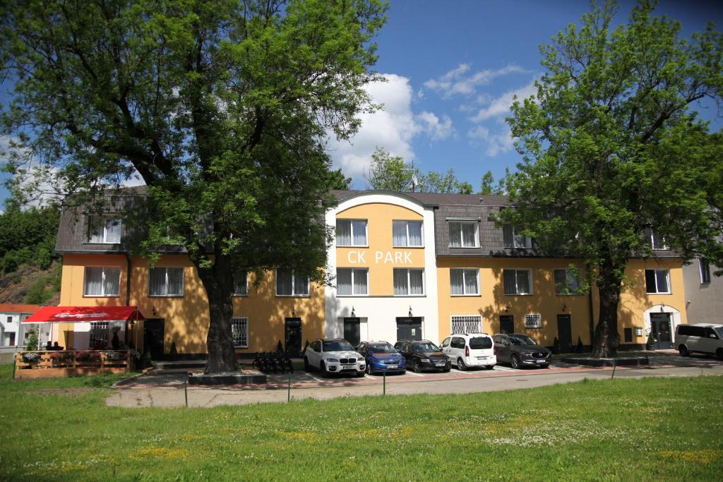 捷克克鲁姆洛夫Hotel CK Park的一座黄色的大建筑,停车场有车辆停放