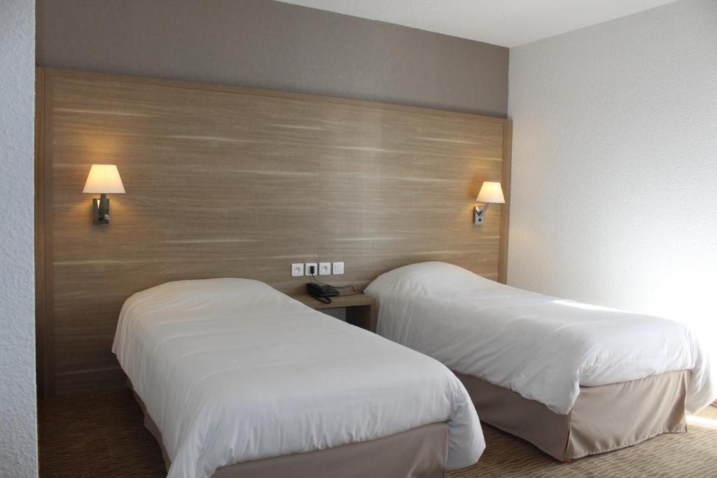 迪纳尔林登酒店的配有白色床单的酒店客房内的两张床