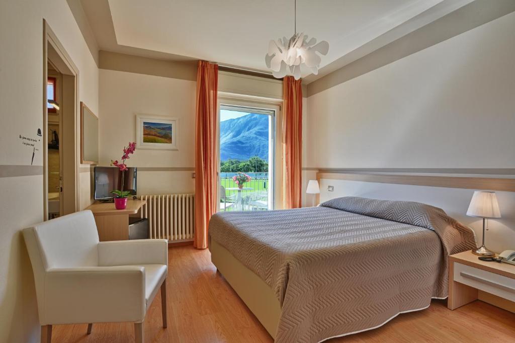 索里科Hotel Europa - Sorico的卧室配有床、椅子和窗户。