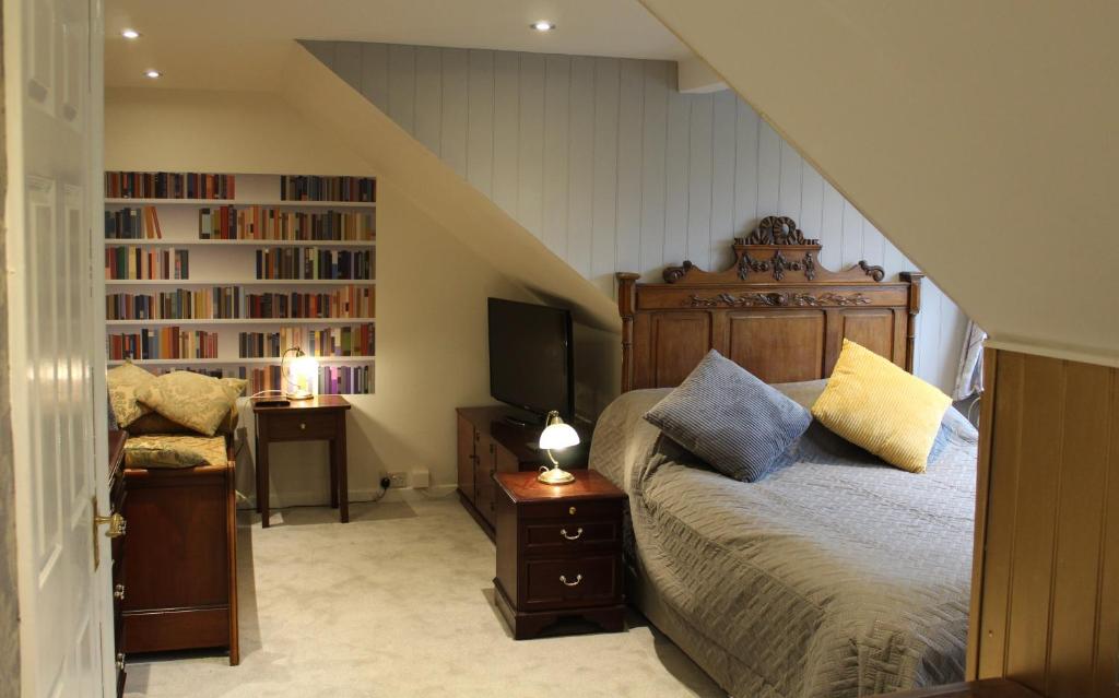 格拉斯顿伯里海顿之家旅馆的一间卧室配有一张床、一台电视和书架