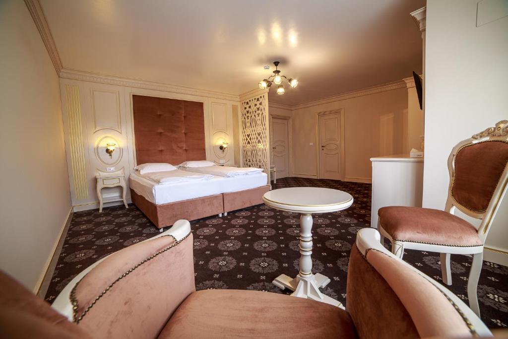 坎普朗莫道尼斯Grădina Mariajelor Hotel的一间卧室配有两张床和一张桌子及椅子