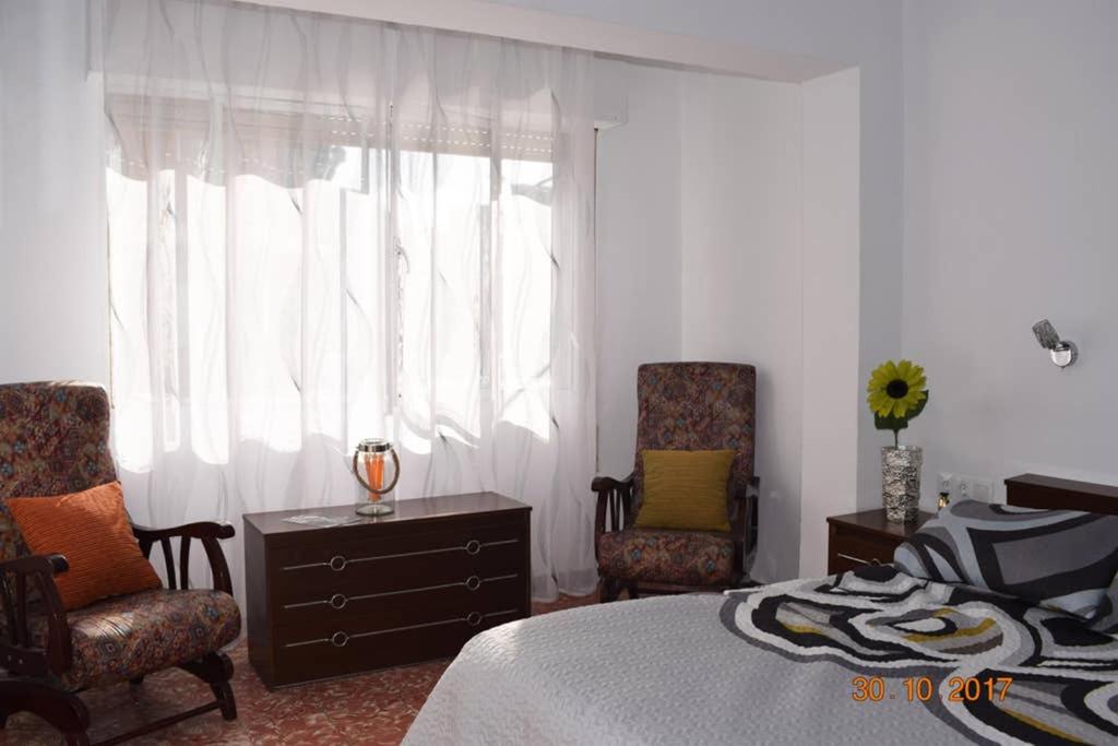 阿利坎特Apartamento en el centro de Alicante的一间卧室配有一张床、两把椅子和一个窗户