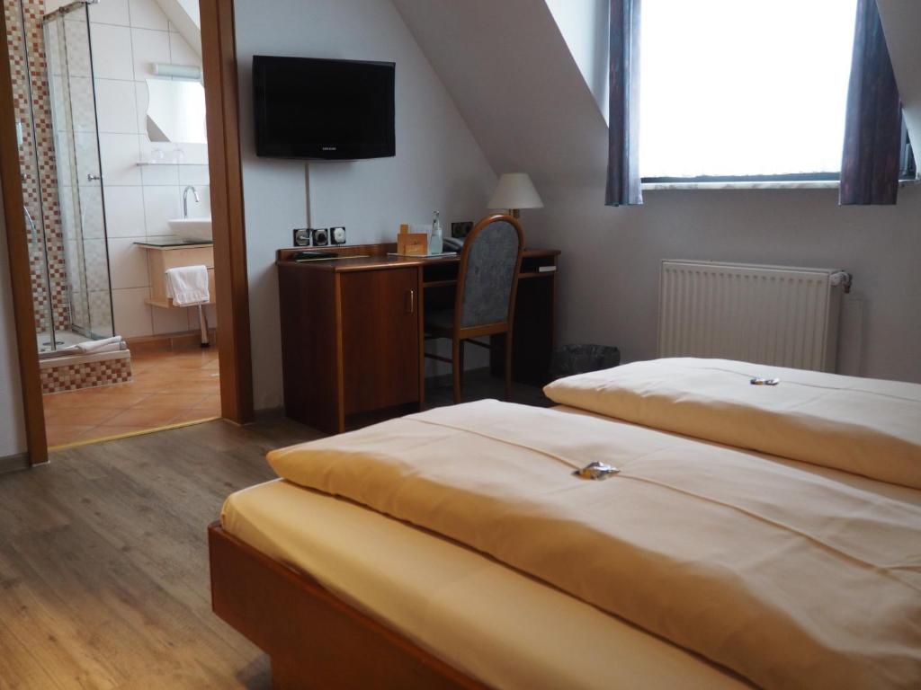 科尔申布罗赫比勒费尔德酒店的一间卧室配有两张床、一张桌子和一台电视。