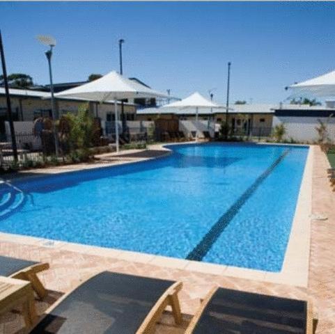 杰拉尔顿布罗德沃特水手度假酒店的一个带桌子和遮阳伞的大型蓝色游泳池