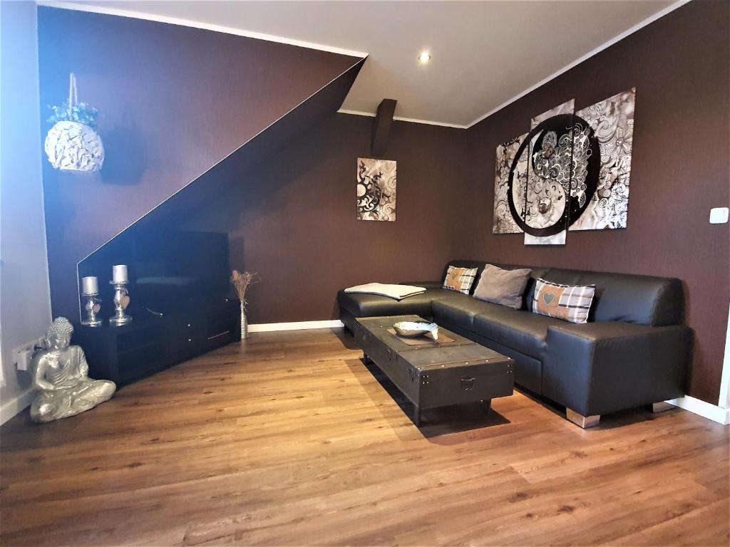卡尔斯哈根Ferienwohnung Jamie的客厅设有黑色真皮沙发和楼梯。