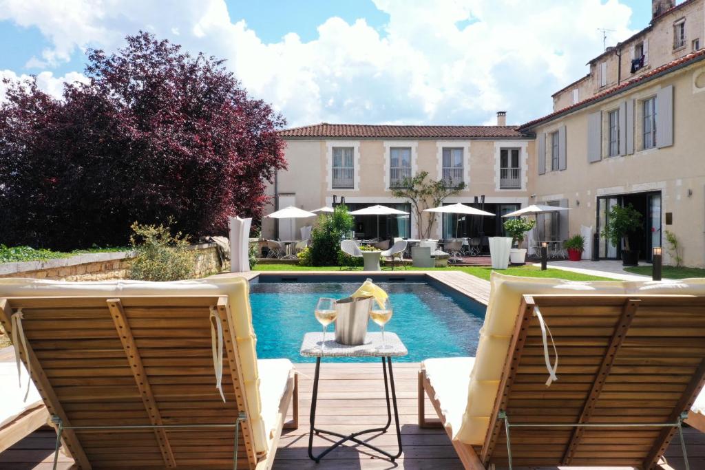 昂古莱姆Hotel Le Saint Gelais的一个带两把椅子的庭院和一个游泳池