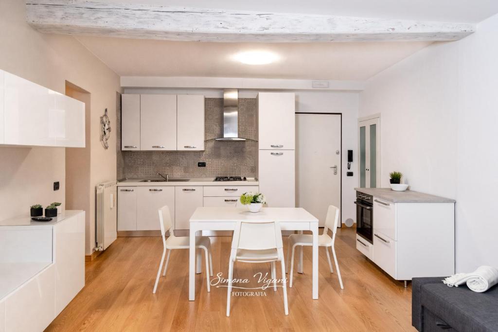 洛韦雷Feel at Home - NEL CUORE DI LOVERE的厨房以及带白色桌椅的用餐室。
